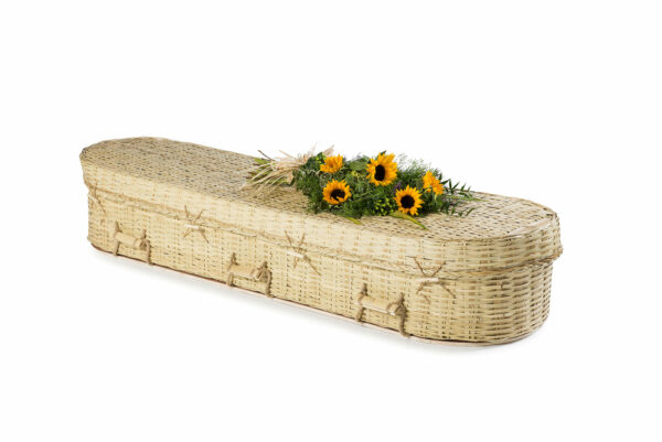 White Wicker rounded coffin with flowers on