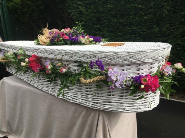 White wicker coffin with flowers