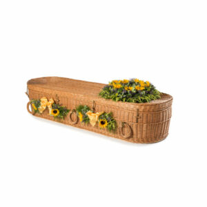 Wicker rounded coffin with flowers on