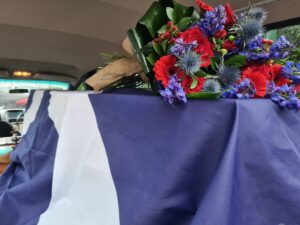 Flag draped over coffin with flowers