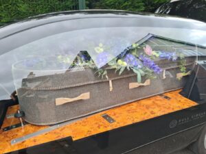 Wool coffin with blue flowers in eco hearse