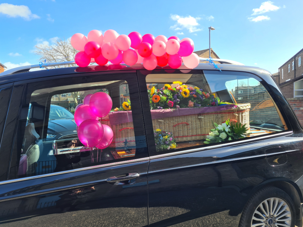 Pink balloons on traditional hearse