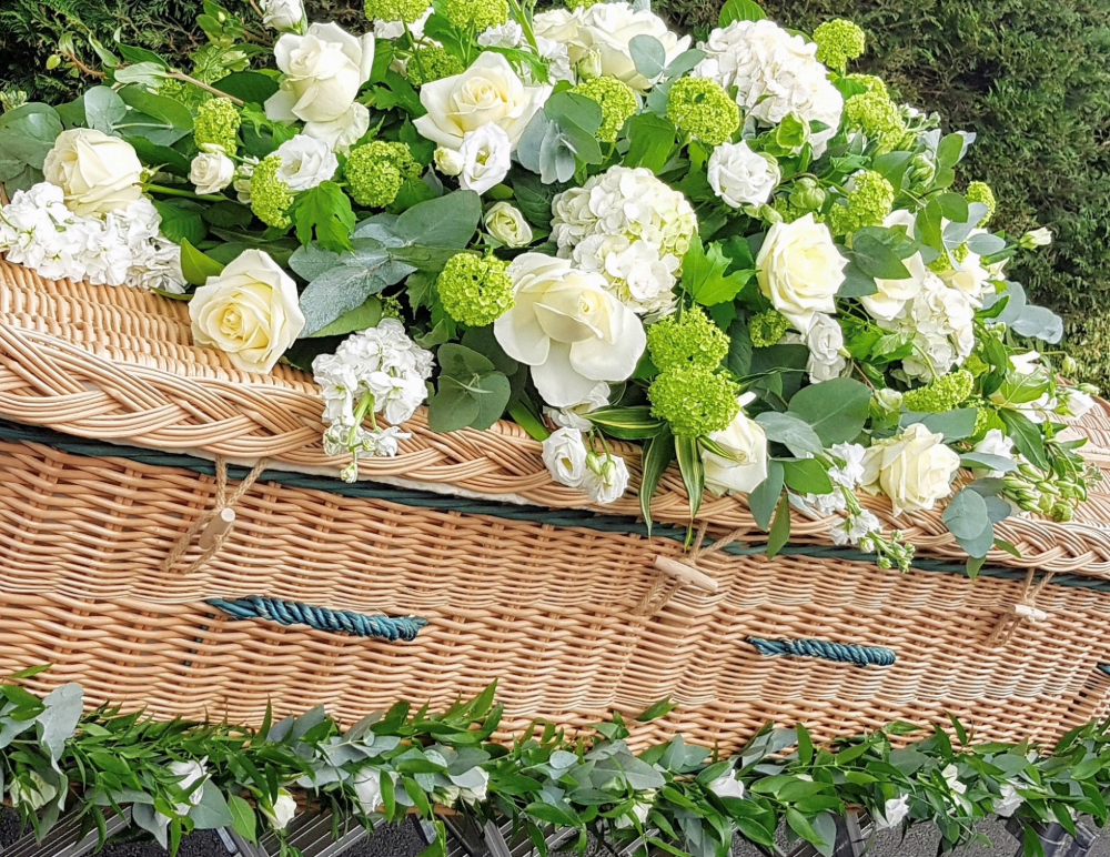 White flower spray on wicker coffin