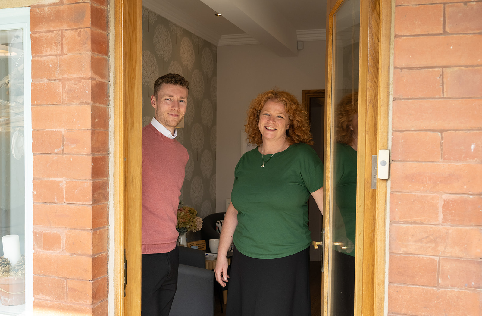 Two friendly team members holding the door open for someone to enter our funeral building