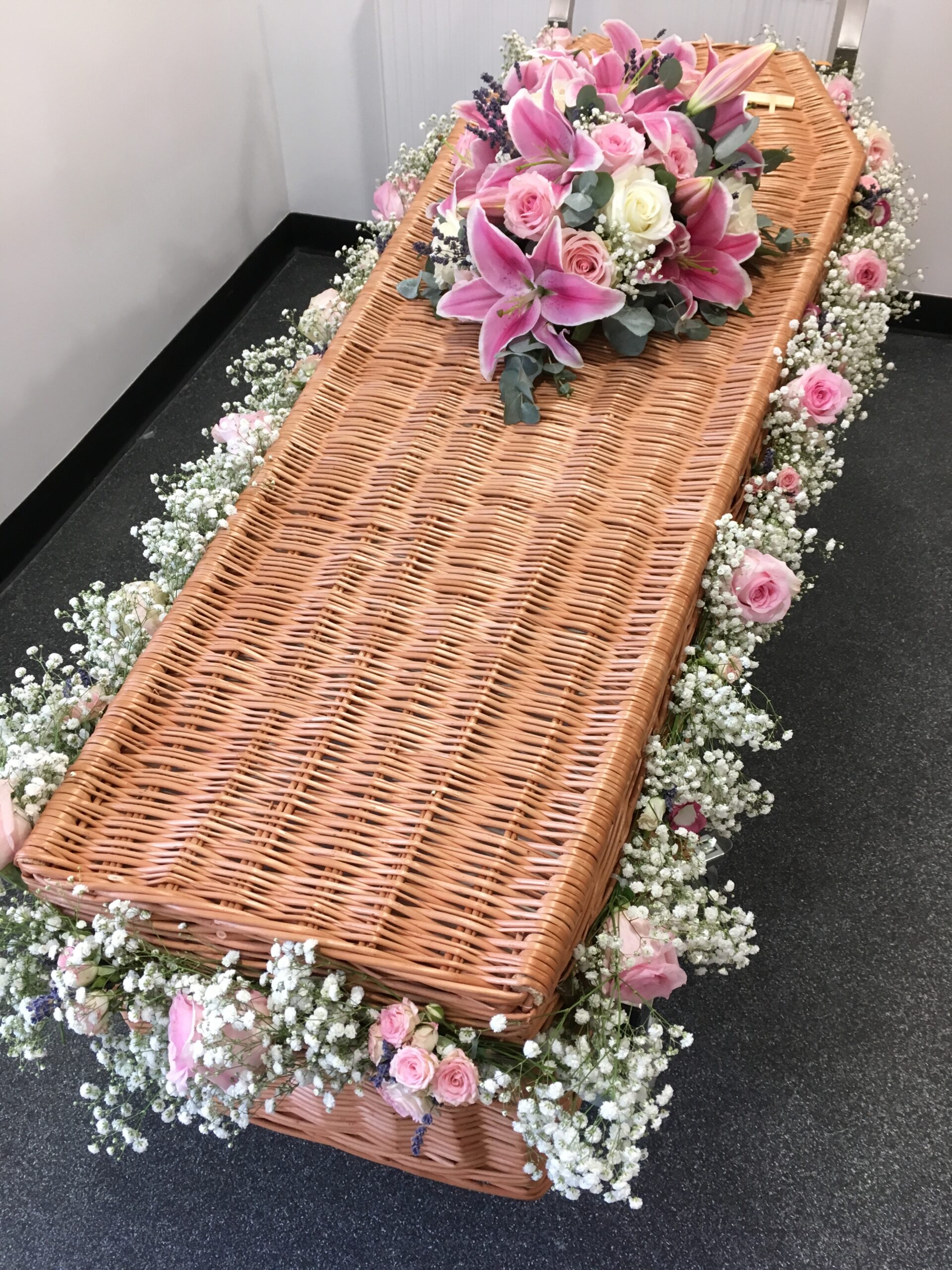 Wicker coffin with pink and white garland