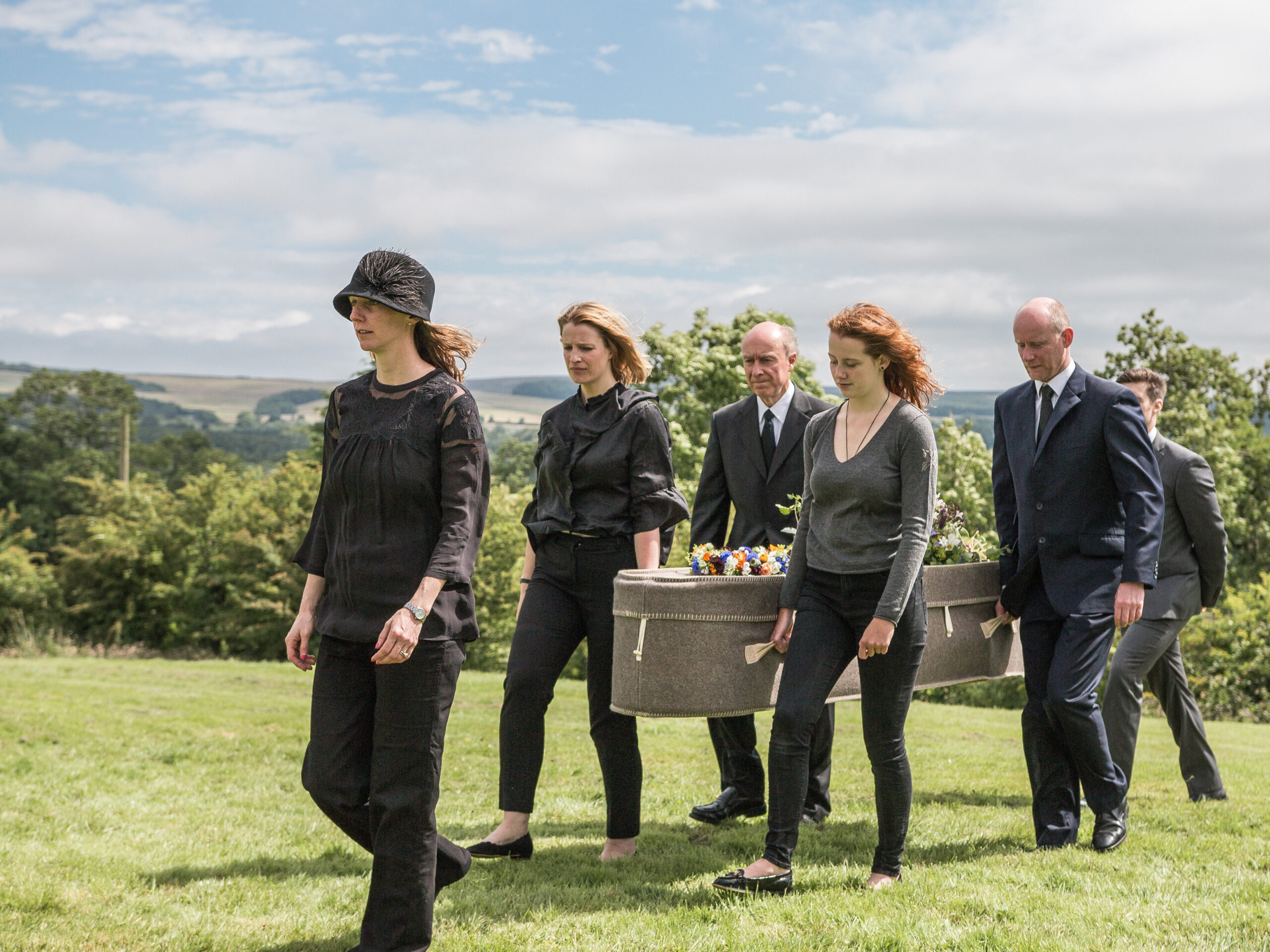 Four people dressed in black carrying atn alternative woollen coffin during an alternative funeral