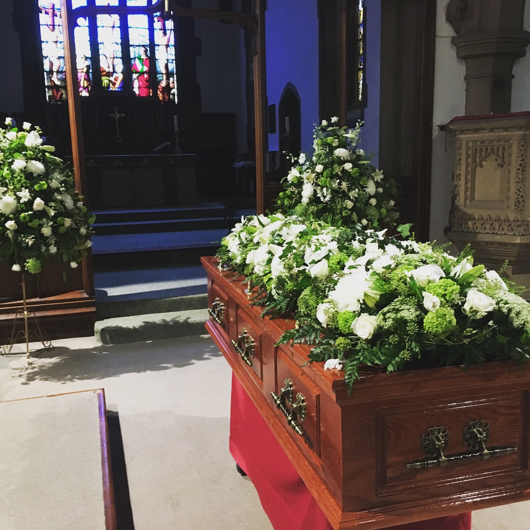 Traditional funeral, wooden casket in church with white flowers